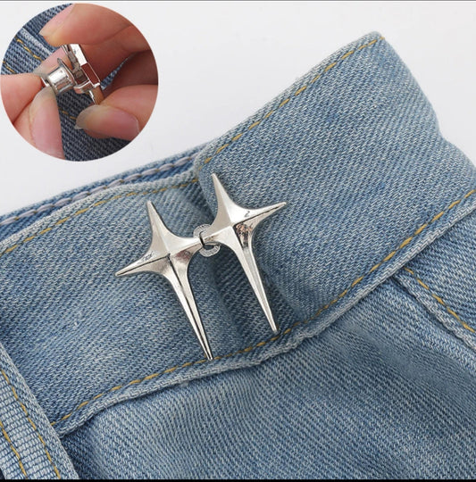 Silver star-shaped pin on denim fabric with close-up of clasp.